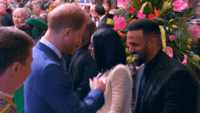 a man in a blue suit is talking to a woman in a white dress in front of a bbc sign