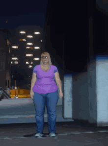 a woman in a purple shirt and blue jeans is standing in a parking lot at night