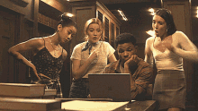 a group of people are looking at a laptop screen