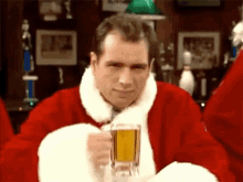 a man dressed as santa claus is holding a glass of beer in a bar .