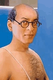 a shirtless man wearing glasses and a hairy chest is looking at the camera .