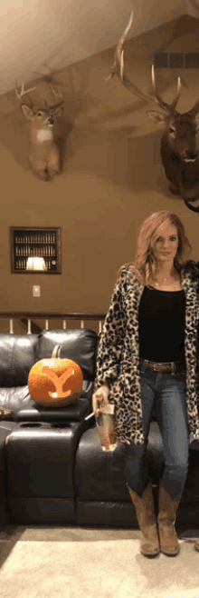 a woman in a leopard print coat stands in front of a pumpkin