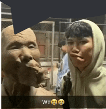 a man in a hoodie is making a face next to a statue of an old man