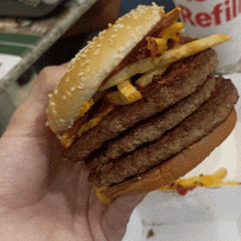 a person is holding a hamburger in front of a mcdonald 's refill container