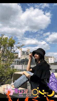 a woman wearing a black hat sits on a bench with a picture of a butterfly and the word soymon on it