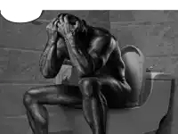 a naked man is sitting on a toilet with his head in his hands