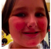 a young girl with red cheeks is smiling for the camera