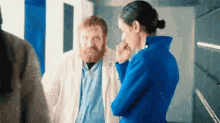 a man with a beard is standing next to a woman in a blue coat .