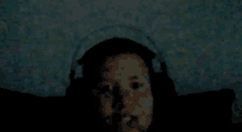 a person wearing headphones is laying down in the dark .