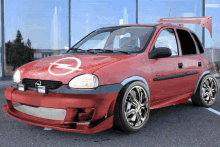 a red opel car is parked in front of a window