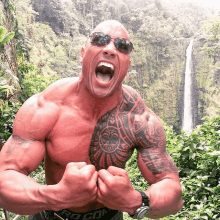 a shirtless man with a tattoo on his chest is standing in front of a waterfall wearing sunglasses