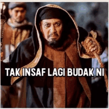 a man with a beard is holding a rope and has the words tak insaf lagi budak ni above him