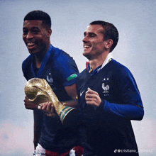 two soccer players are holding a trophy and one has a medal around his neck with a rooster on it