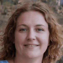 a close up of a woman 's face with curly hair and blue eyes