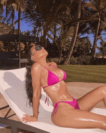 a woman in a pink bikini is laying on a white chair