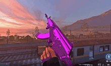 a person holding a purple gun in front of a train with the number 45 on it