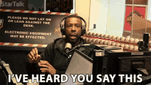 a man wearing headphones in front of a sign that says " please do not lay on or lean against the desk "