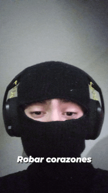 a person wearing headphones and a ski mask with the words robar corazones on the bottom right