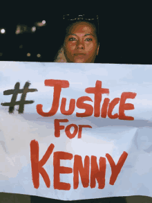 a woman holds a sign that says #justice for kenny