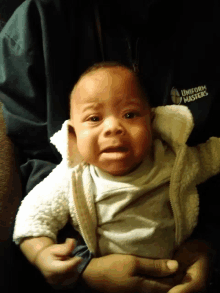 a baby is being held by a man wearing a uniform masters shirt