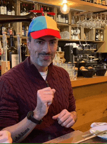 a man wearing a red sweater and a colorful hat