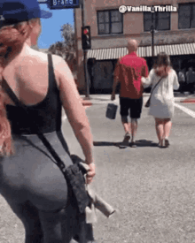 a woman in a black tank top is walking down a street with a man in a red shirt .