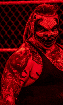 a wrestler with dreadlocks and a scary mask is standing in front of a chain link fence