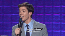 a man in a suit and tie holds a microphone and says " platonic " on the screen