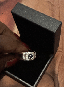 a person is holding a ring in a box with the letter i on it