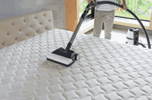 a person is using a vacuum cleaner on a mattress