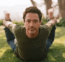 robert downey jr. is doing yoga on the grass .