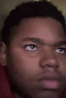 a close up of a young man 's face with his eyes looking up