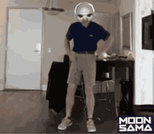 a man in a blue shirt and grey shorts is dancing in a room with a moon sama logo