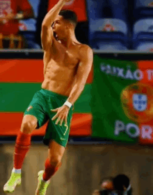 a shirtless soccer player is jumping in the air in front of a flag that says portugal .