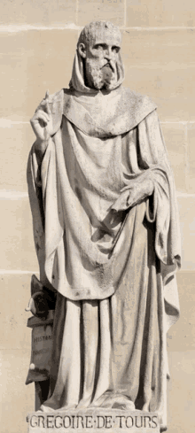 a statue of gregore de tours is standing in front of a brick wall