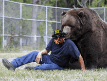 a man wearing a hat that says zoo zoo is laying next to a bear