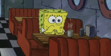 spongebob squarepants sits at a table with a cup of coffee