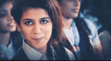 a group of young people are sitting in a theater watching a movie and a girl is smiling at the camera .