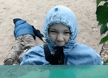 a young boy wearing a blue hooded jacket looks at the camera .