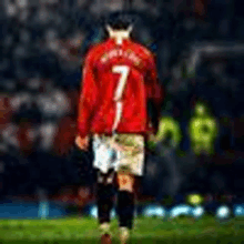 a soccer player in a red jersey is walking on a field .