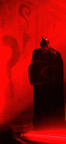 a silhouette of batman is against a red wall