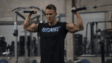 a man wearing a black shirt that says beast is working out in a gym