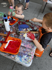 two young boys are playing with paint on a table that has a potato apron on