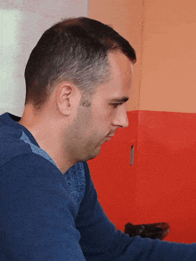 a man sitting in front of a red wall with chinese characters on it