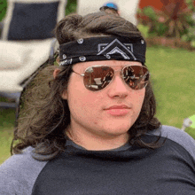 a young man with long hair is wearing sunglasses and a bandana .