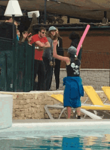 a woman wearing a black shirt with a skull and crossbones on it stands in front of a swimming pool