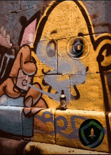 a bottle of beer sits on a brick wall next to graffiti