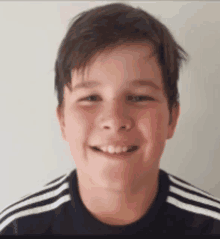 a young boy wearing a black and white striped shirt smiles for the camera