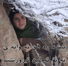 a woman in a green scarf is sticking her head out of a hole in a tree covered in snow .