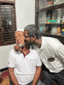 a man kissing another man 's cheek who is wearing a shirt that says save 4 ashes